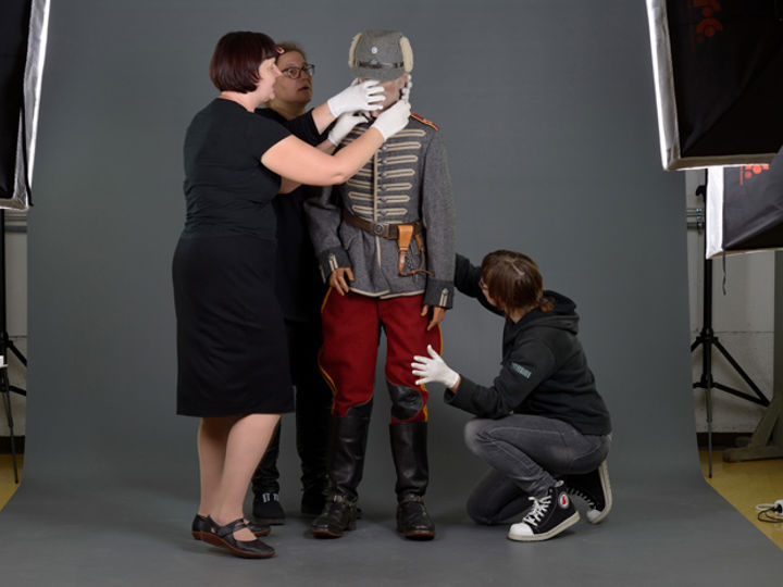 Museon kokoelmatyöntekijät asettelevat mallinuken ylle 1920-ja 30-luvuilla käytettyä ratsuväen asepukua.